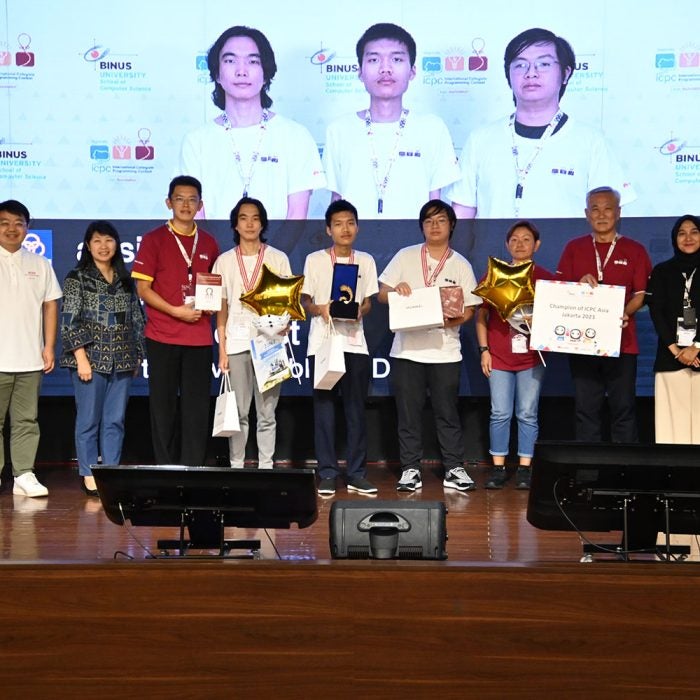 NUS Computing Associate Professor Steven Halim (fourth from left) and Associate Professor Tan Sun Teck (third from right) poses with the three Team absinthe members (centre) in white T-shirts, at ICPC Asia Jakarta Regional Contest. Team absinthe (from L to R): Nyamdavaa Amar, Bui Hong Duc, and Rama Aryasuta Pangestu.